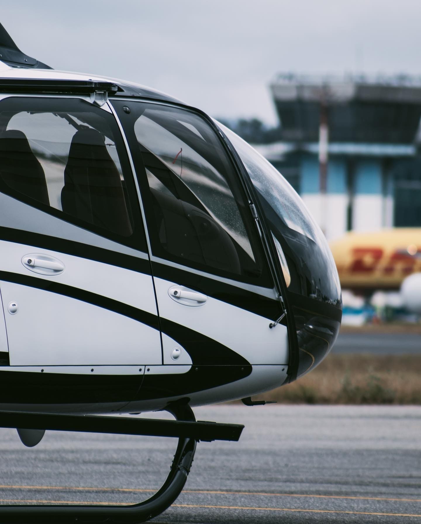 EC130 helicopter in profile at La Aurora airport, with the terminal building in the background