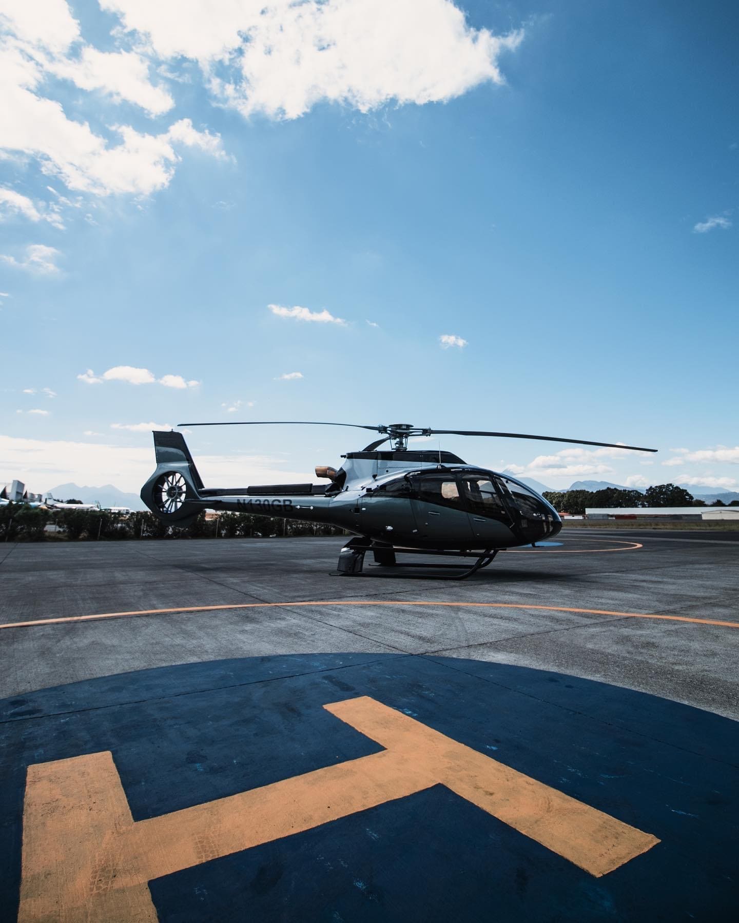 EC130 helicopter parked on the helipad at La Aurora, mountains in the background